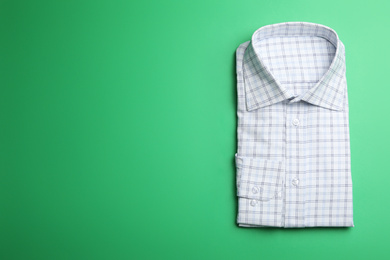 Photo of Male stylish shirt with pattern on green background, top view. Space for text