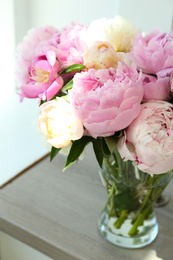 Bouquet of beautiful peonies in vase on wooden table