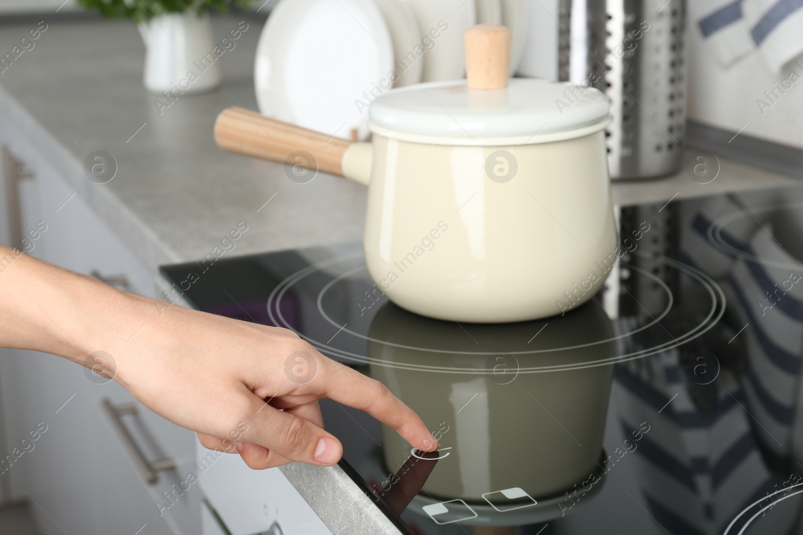 Photo of Woman adjusting electric oven cooktop in kitchen, closeup