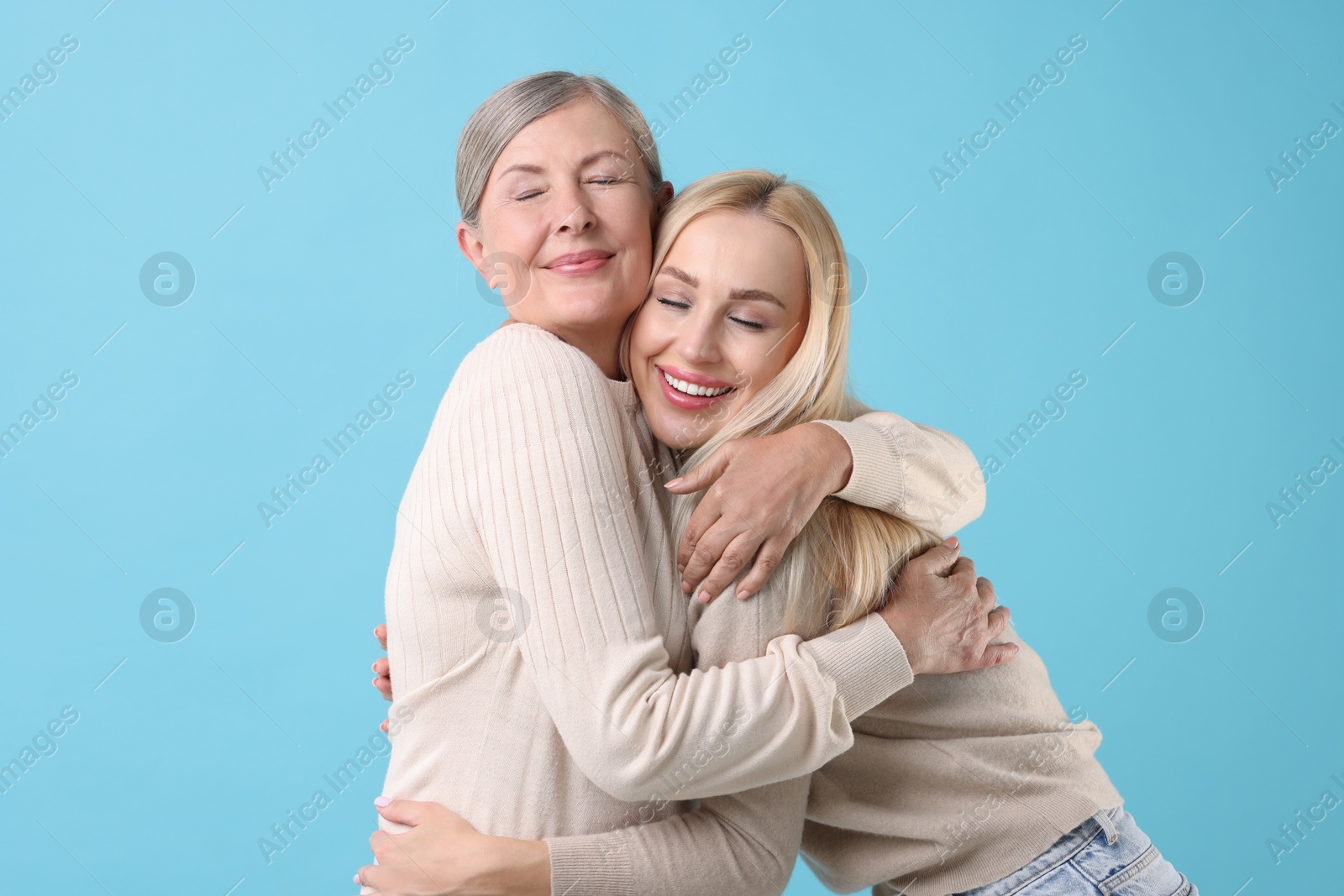 Photo of Family portrait of young woman and her mother on light blue background