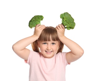 Portrait of little girl holding broccoli as horns on white background