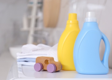 Bottles of detergent and children's clothes on countertop in bathroom