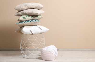 Photo of Stack of soft pillows on small table indoors. Space for text