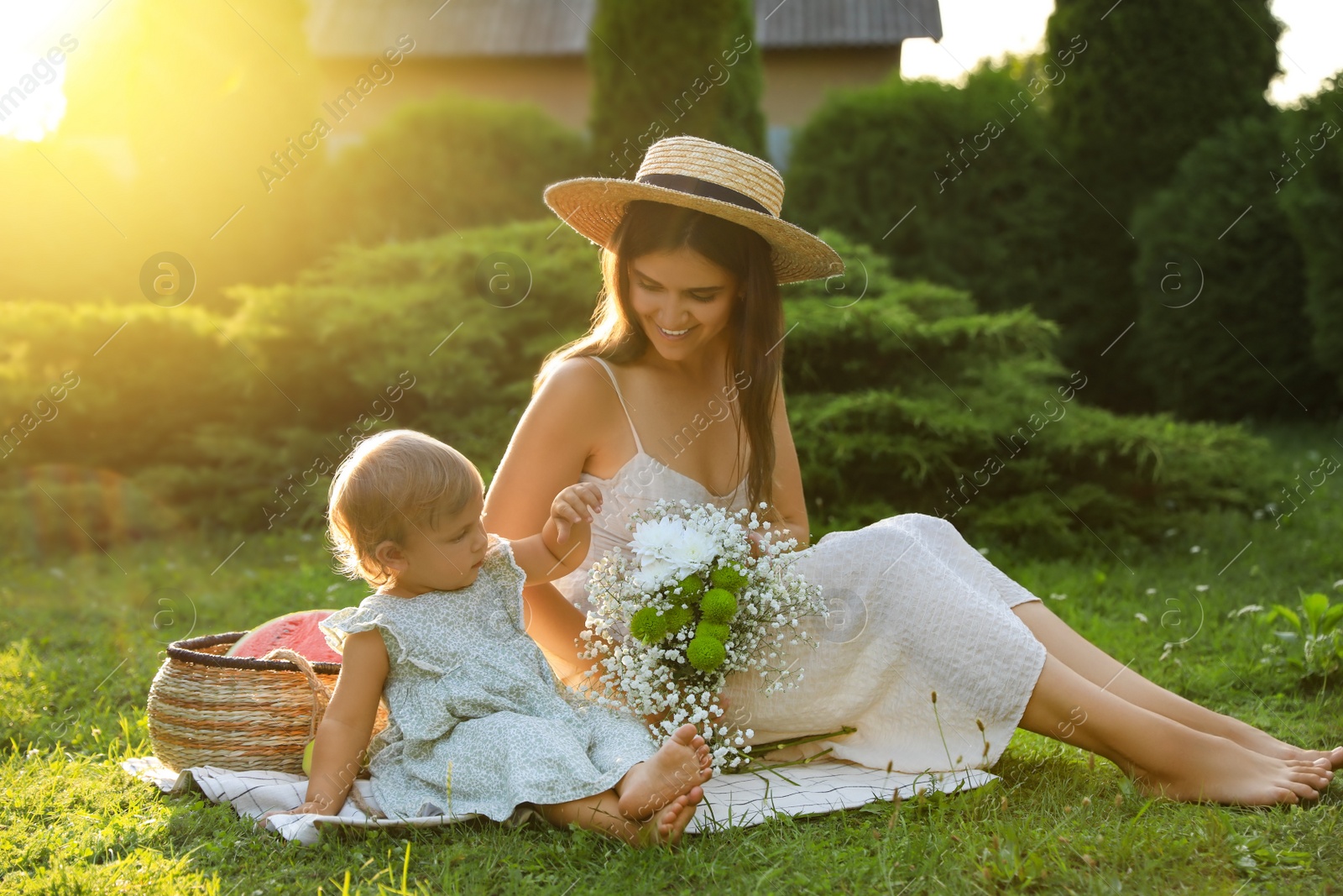 Photo of Mother with her baby daughter having picnic in garden on sunny day