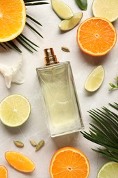 Flat lay composition with bottle of perfume and fresh citrus fruits on light marble background