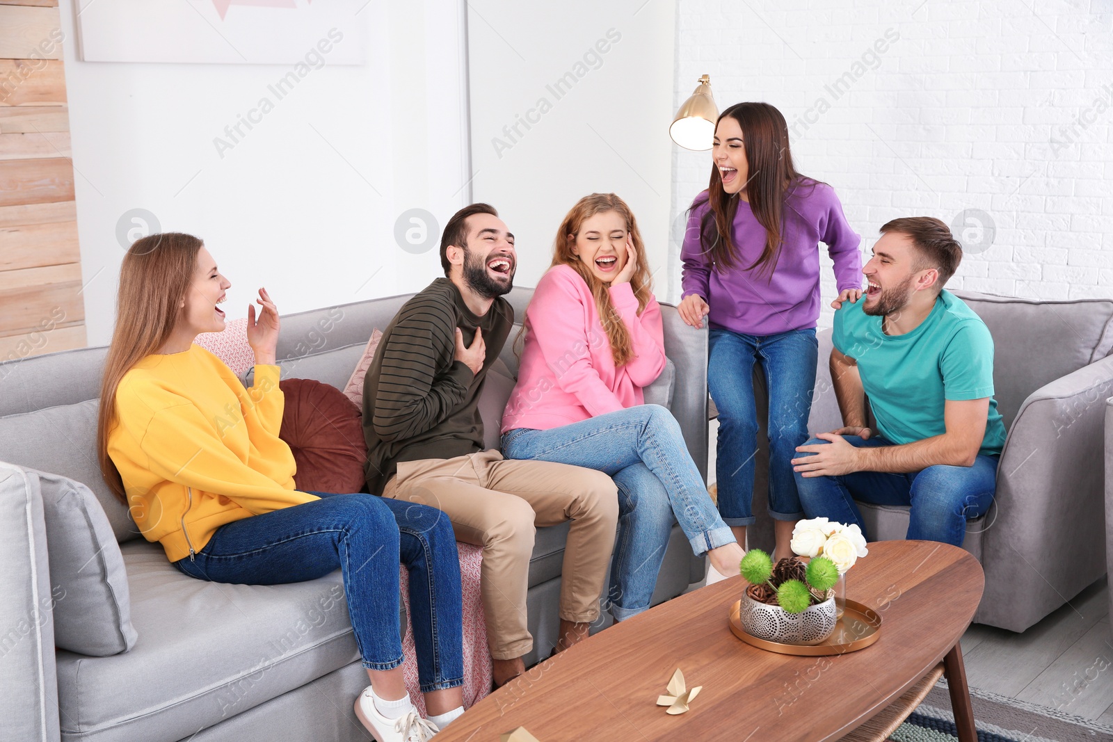 Photo of Group of friends telling jokes and laughing in living room