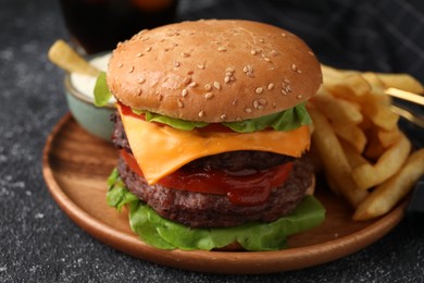 Photo of Tasty cheeseburger with patties, sauce and French fries on grey textured table, closeup