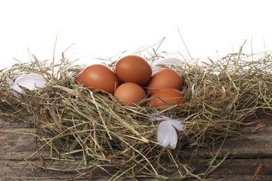 Fresh raw chicken eggs in nest on wooden table against white background