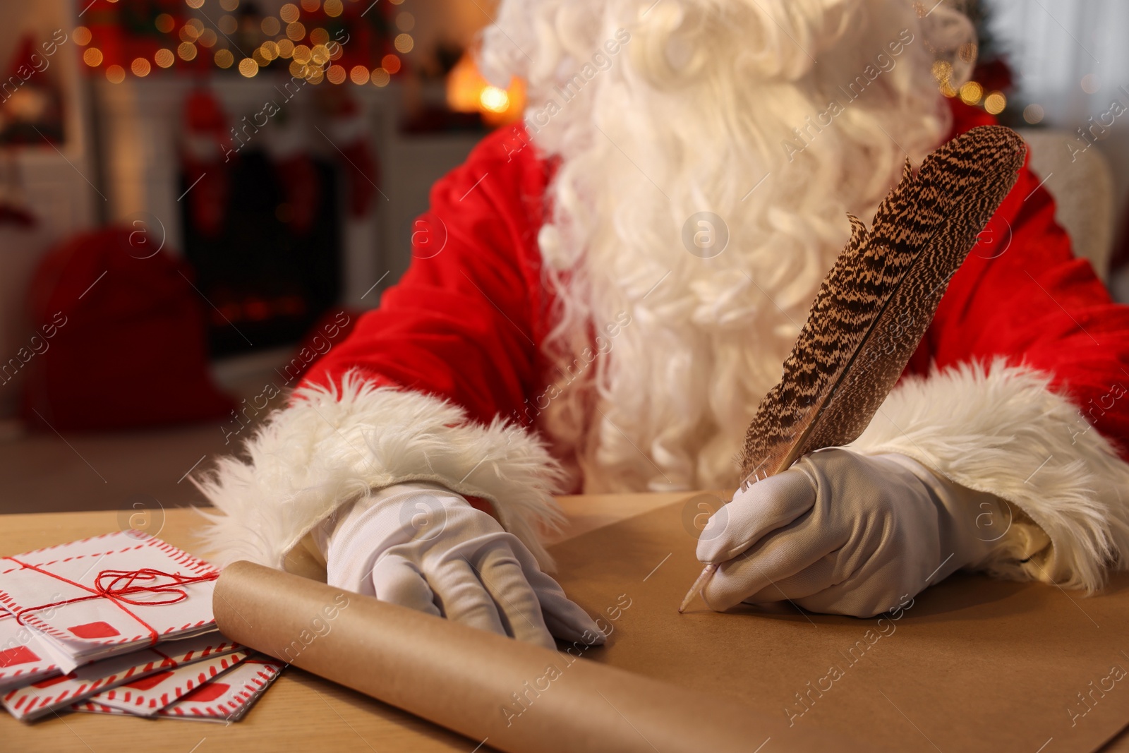Photo of Merry Christmas. Santa Claus writing letter at table in room, closeup