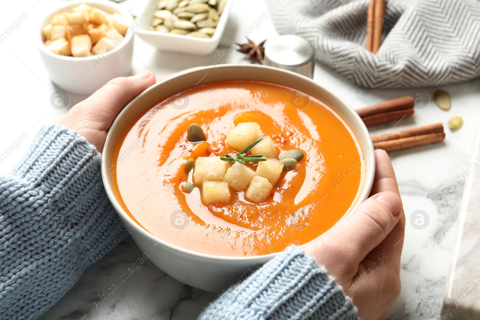 Photo of Woman with bowl of tasty sweet potato soup at table, closeup