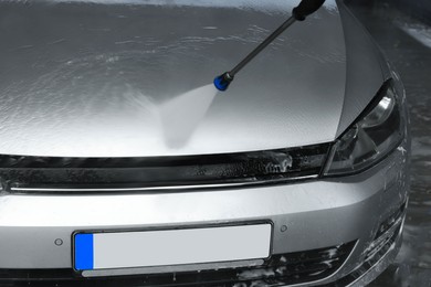 Photo of Washing auto with high pressure water jet at outdoor car wash, closeup