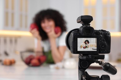 Food blogger recording video in kitchen, focus on camera