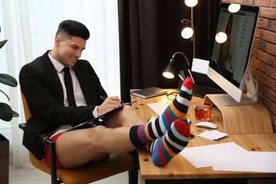 Photo of Businessman in jacket and underwear having videocall on computer at home office