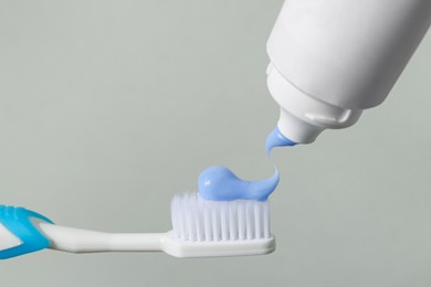 Photo of Applying paste on toothbrush against grey background, closeup