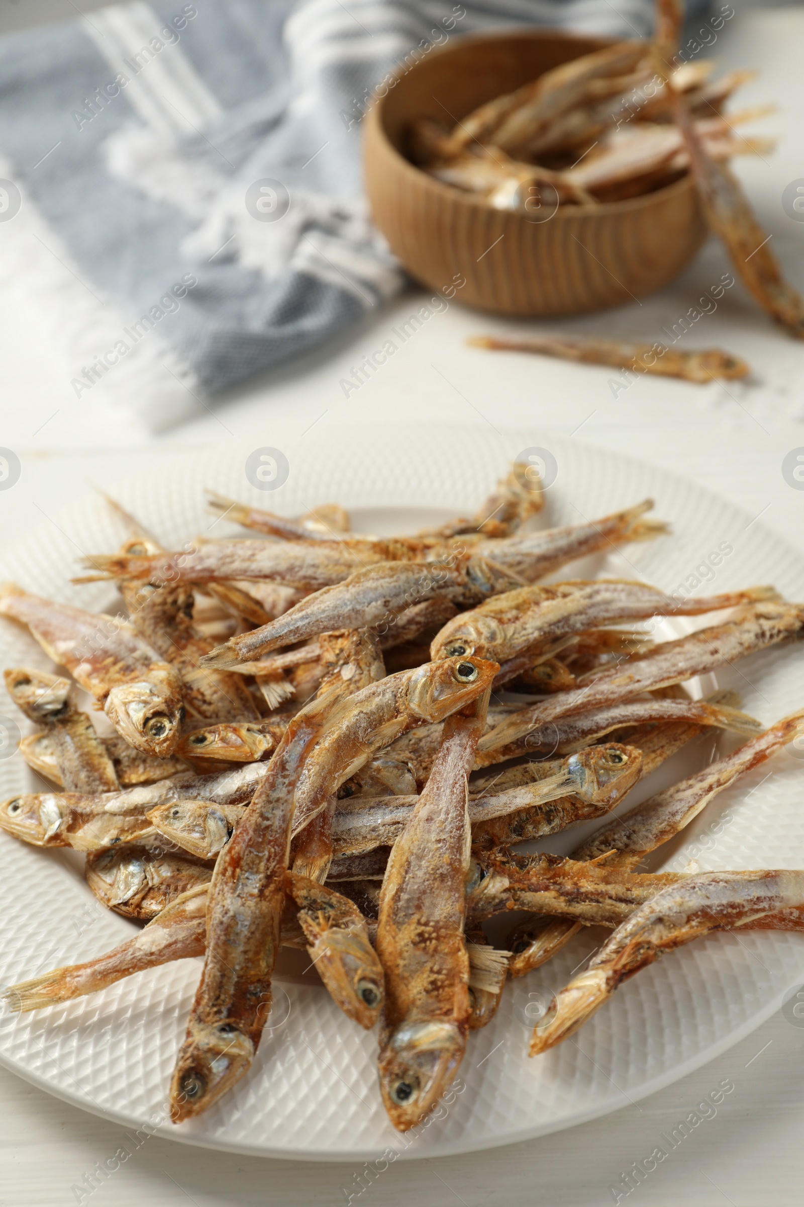 Photo of Plate with tasty dried anchovies on white table, closeup