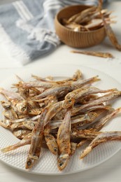 Photo of Plate with tasty dried anchovies on white table, closeup