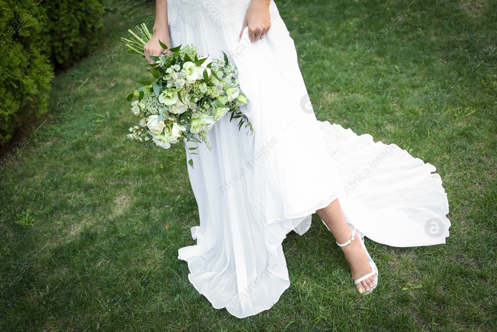 Photo of Bride in beautiful wedding dress with bouquet outdoors, closeup