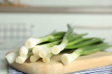 Photo of Fresh green spring onions on wooden board, closeup