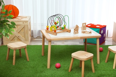 Stylish playroom interior with toys and modern wooden furniture