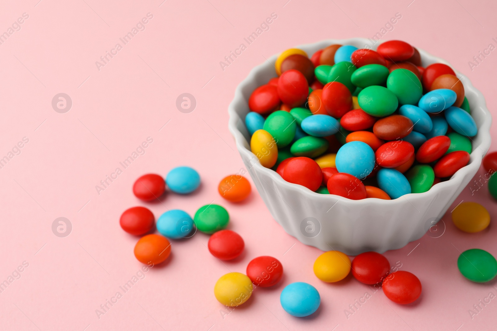 Photo of Tasty colorful candies on pink background, closeup. Space for text