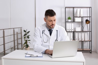 Photo of Pediatrician working on laptop at desk in office