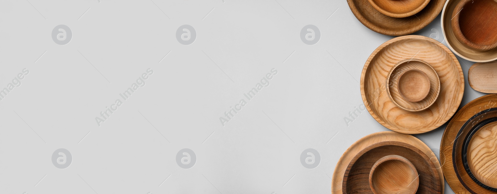 Image of Set of different wooden dishes on light grey background, flat lay with space for text. Banner design