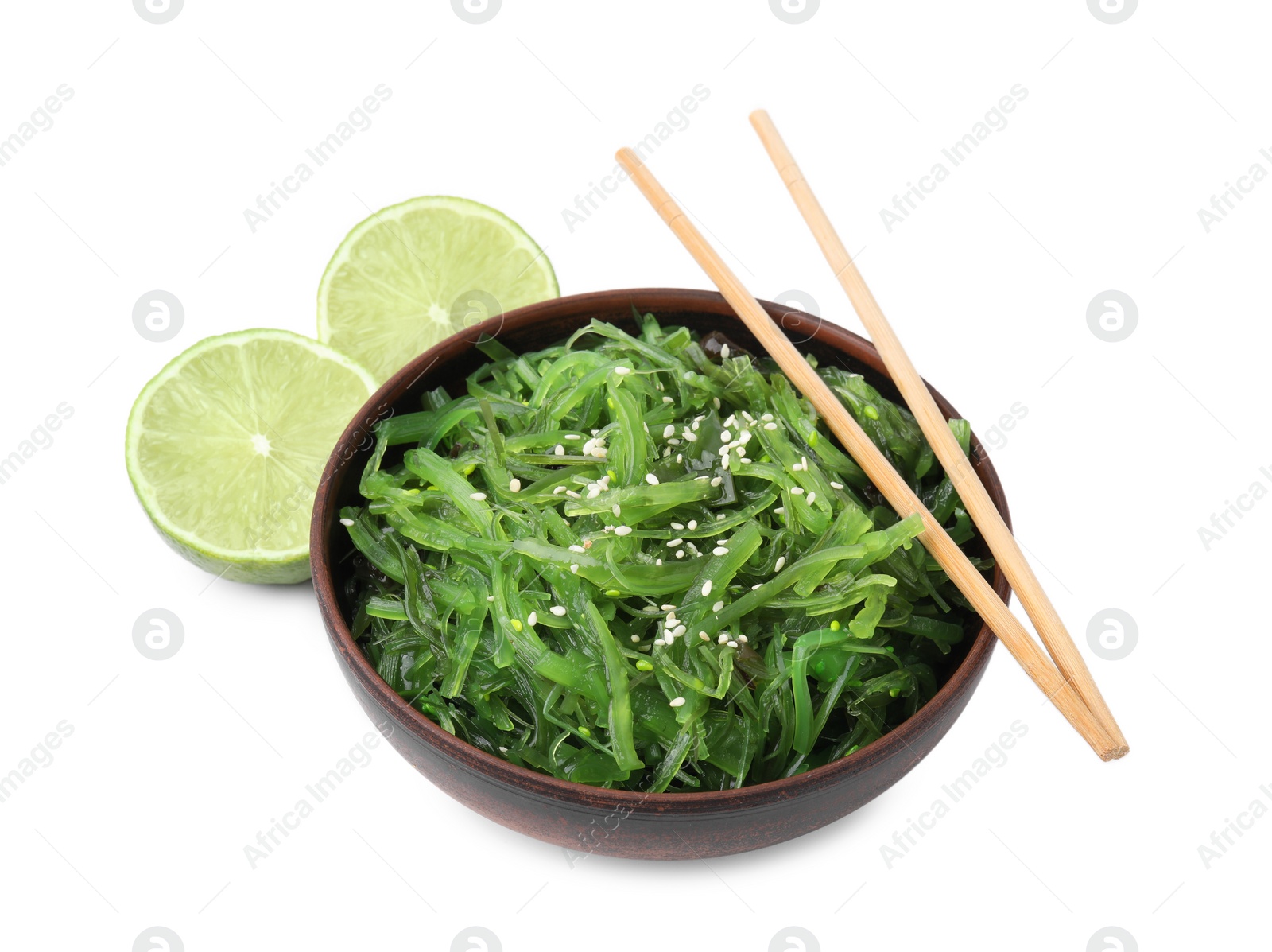 Photo of Tasty seaweed salad in bowl, chopsticks and pieces of lime isolated on white