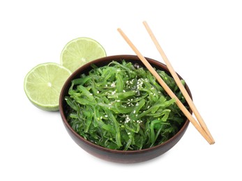 Photo of Tasty seaweed salad in bowl, chopsticks and pieces of lime isolated on white