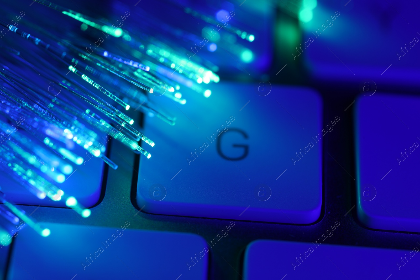 Photo of Optical fiber strands transmitting different color lights on computer keyboard, macro view