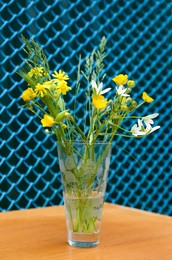 Photo of Bouquet of beautiful wildflowers in glass vase on wooden table