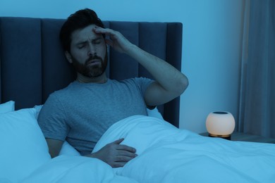 Photo of Man suffering from headache in bed at night