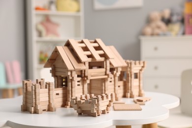 Photo of Wooden entry gate and building blocks on white table indoors. Children's toy