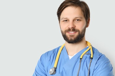 Photo of Doctor or medical assistant (male nurse) with stethoscope on light grey background. Space for text
