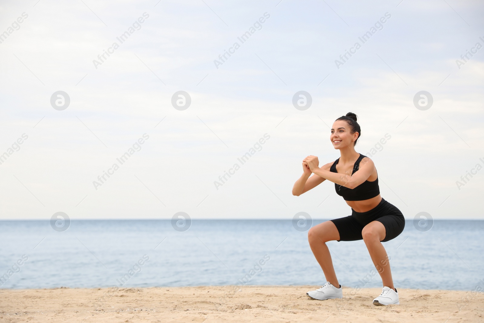 Photo of Young woman doing exercise on beach, space for text. Body training