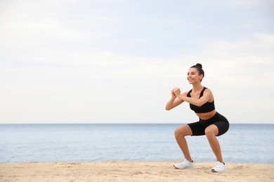 Photo of Young woman doing exercise on beach, space for text. Body training