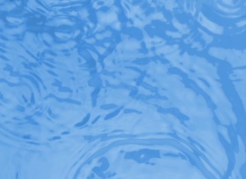 Photo of Concentric waves on blue water surface after falling drops, top view