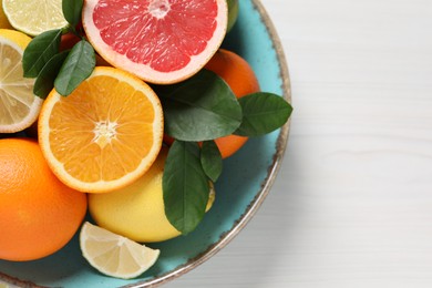 Photo of Different cut and whole citrus fruits on white wooden table, top view. Space for text