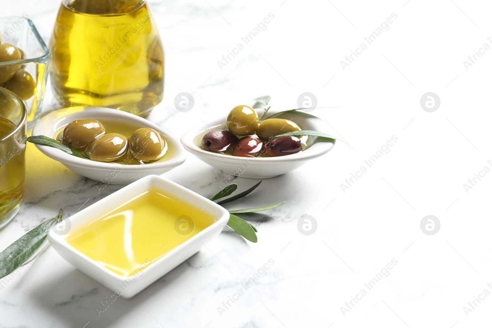 Photo of Bowls with olives and fresh oil on table