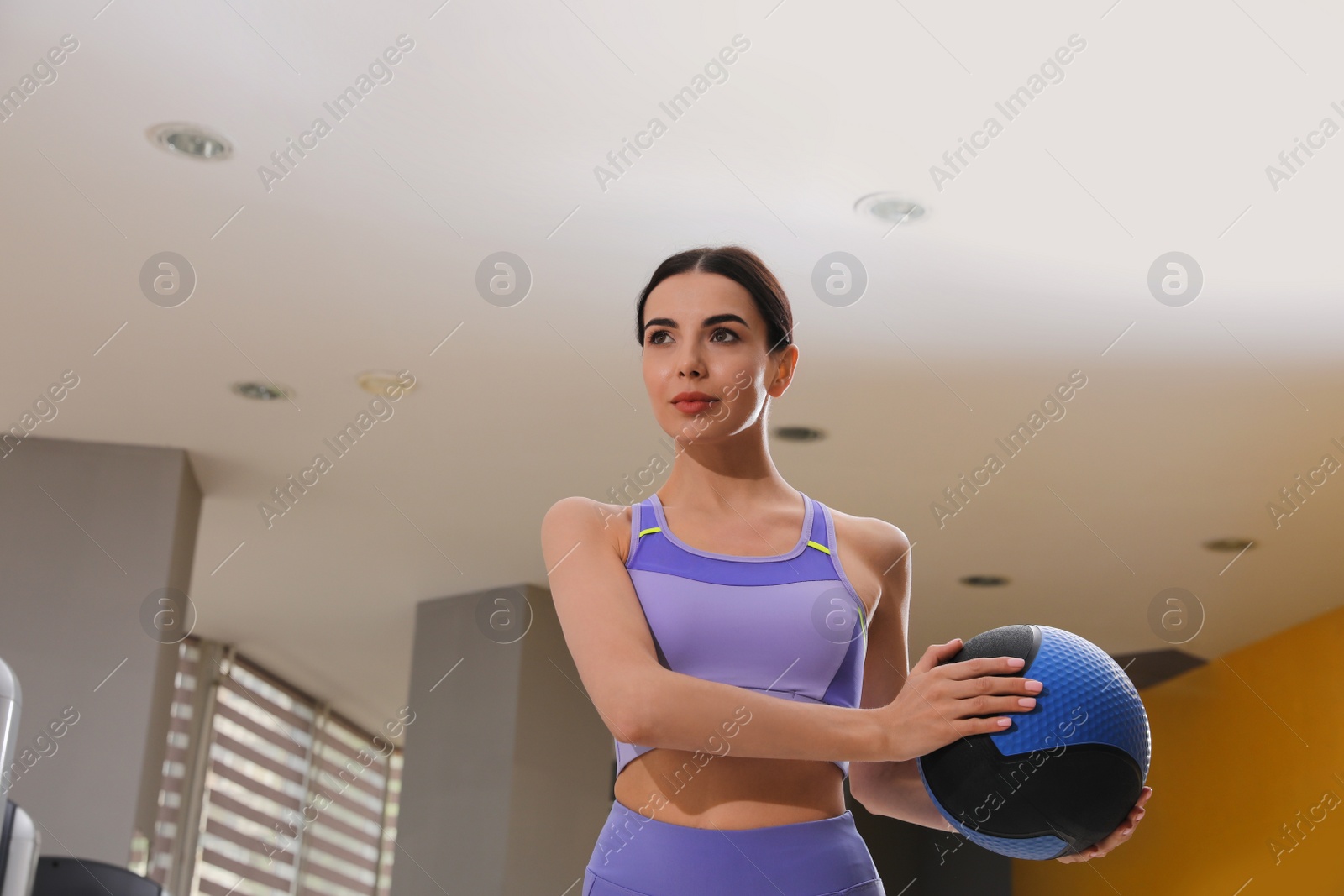 Photo of Young woman exercising with medicine ball in gym, low angle view