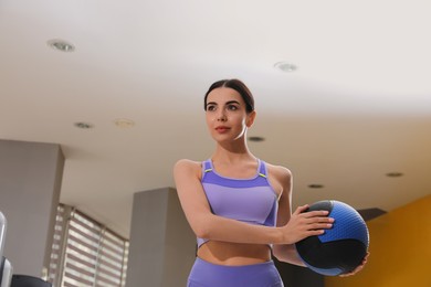 Young woman exercising with medicine ball in gym, low angle view