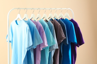 Photo of Men's clothes hanging on wardrobe rack against light background