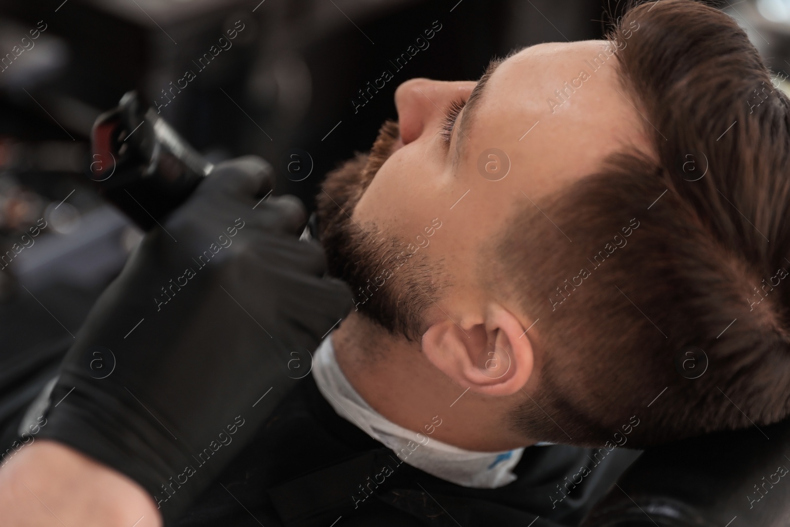 Photo of Professional barber working with client in hairdressing salon. Hipster fashion