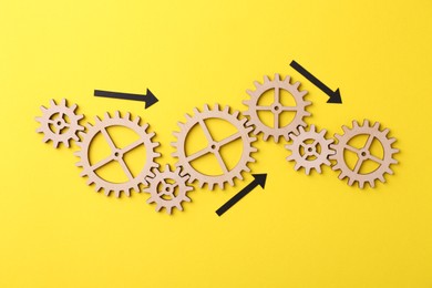 Photo of Business process organization and optimization. Scheme with wooden figures and arrows on yellow background, top view