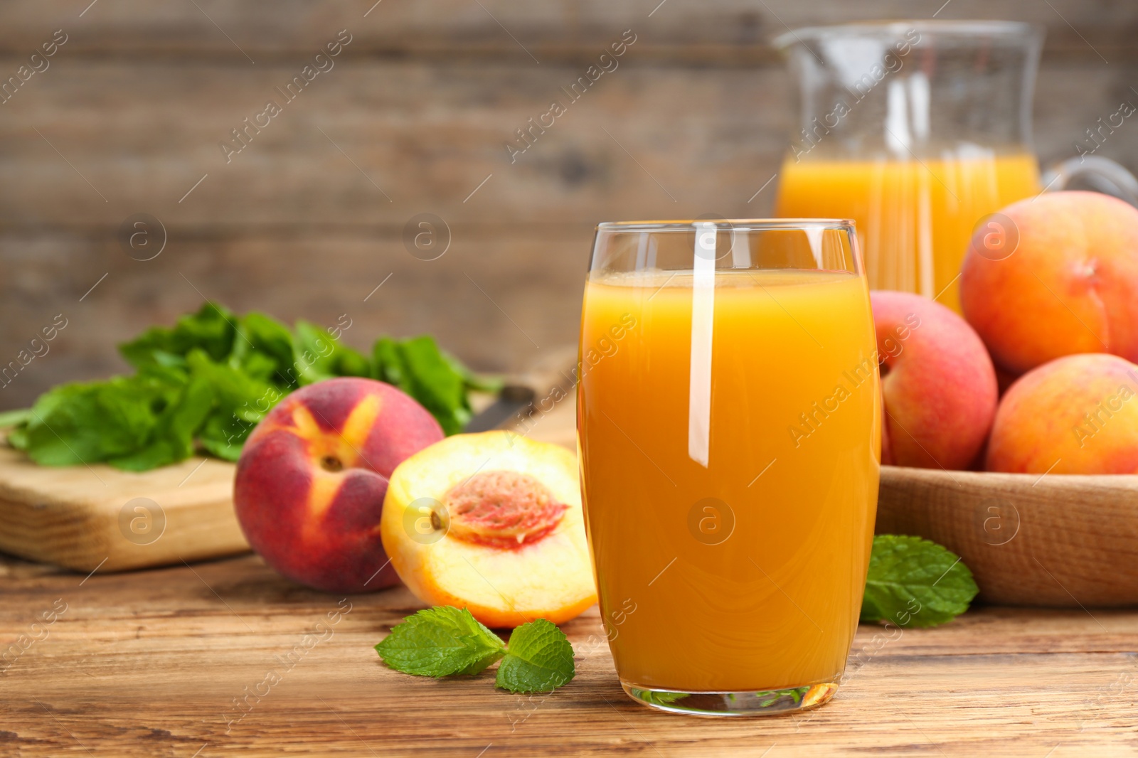 Photo of Natural peach juice and fresh fruits on wooden table