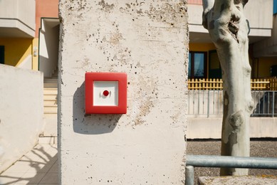 Photo of Red emergency button on stone pillar outdoors