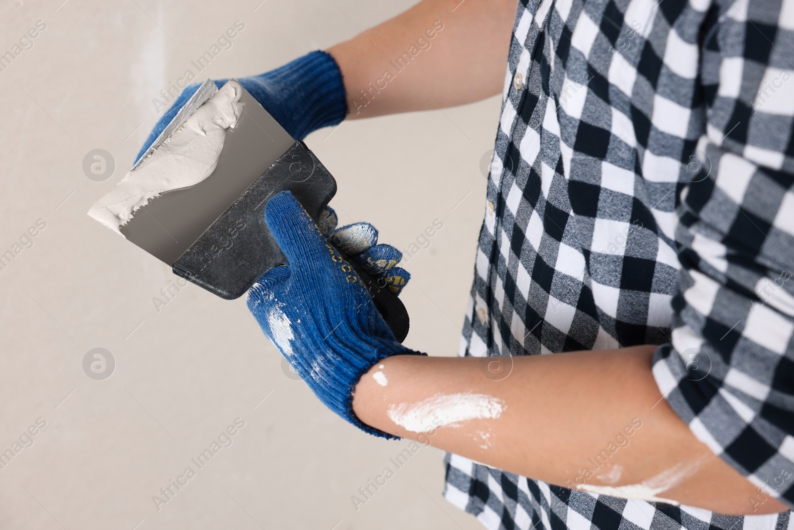 Photo of Worker with putty knives and plaster indoors, closeup. Home renovation