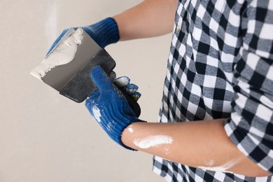 Photo of Worker with putty knives and plaster indoors, closeup. Home renovation