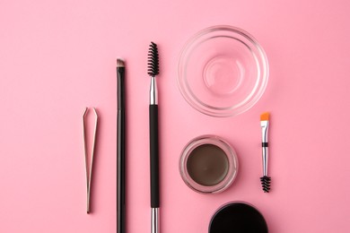 Photo of Eyebrow pomade with henna effect and professional tools on pink background, flat lay