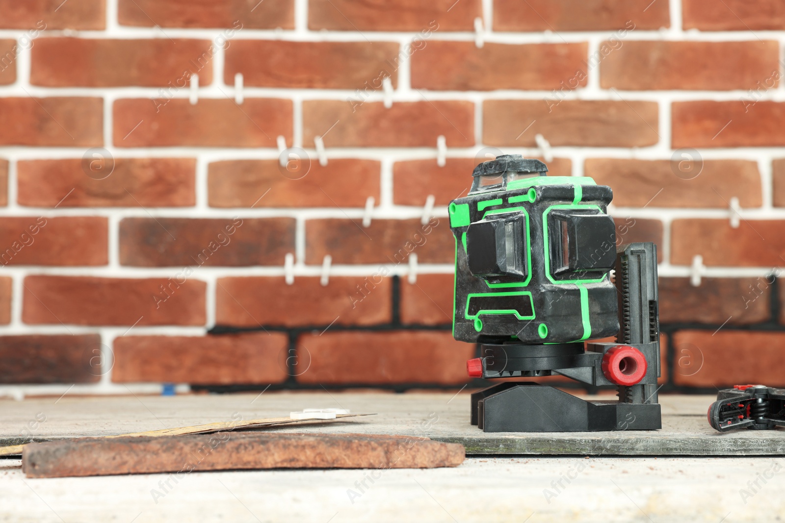 Photo of Modern cross line laser level on floor indoors, space for tex. Tiles installation process