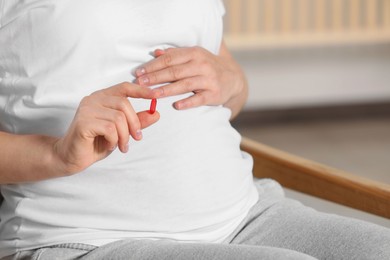 Pregnant woman taking pill indoors, closeup. Space for text